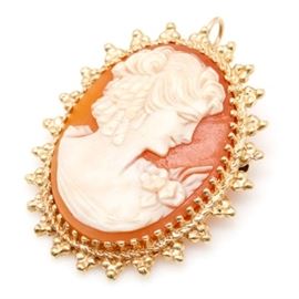14K Yellow Gold Cameo Brooch/Pendant: A 14K yellow gold shell cameo brooch/pendant. This brooch features a decorative prong set shell cameo depicting the profile of a woman. This cameo is surrounded by a setting with milgrain detail.
