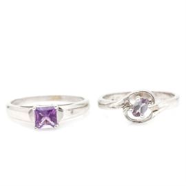 14K White Gold Gemstone Rings: A pairing of 14K white gold gemstone rings. Each ring is prong set with a single stone. One ring has a crown of a square faceted amethyst. The other ring features an openwork criss cross setting that hold an oval faceted color change sapphire.