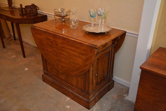 drop-leaf island table with drawer and cabinet on either end 