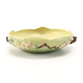 Roseville Pottery Bowl: A vintage Roseville pottery bowl. This ceramic bowl features a light green shade throughout, with raised side designs of branches, flowers and berries. The bowl rim is softly rippled, resembling the edges of flower pedals. Two brown tone handles resembling branches accentuate the sides. The bottom underside is marked “Roseville, U.S.A., 330-10”.