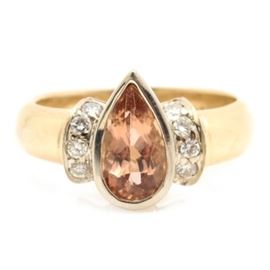 14K Yellow Gold Imperial Topaz and Diamond Ring: A 14K yellow gold ring featuring a bezel set pear shaped faceted 1.23 ct imperial topaz accented by ten round brilliant cut diamonds flanked by brightly polished shoulders.