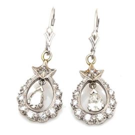 14K White Gold 1.39 CTW Diamond Drop Earrings: A pair of 14K white gold 1.39 ctw diamond drop earrings. Each earring features a diamond encrusted scalloped pear shaped body with foliate accents and an open center housing a single prong set dangling diamond.