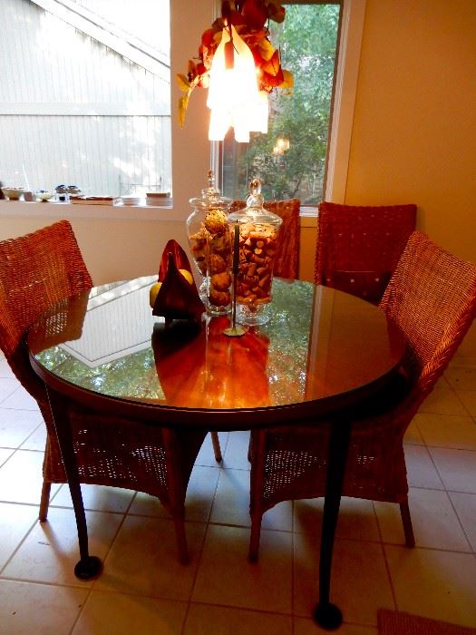 A VERY INTERESTING METAL TABLE WITH A GLASS TOP AND FOUR WICKER CHAIRS 