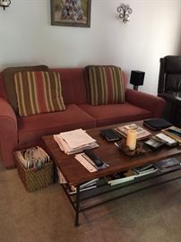 Rust upholstered sofa sleeper and wood and wrought iron coffee table