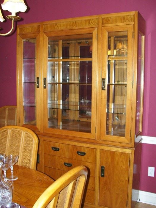 Lighted china cabinet with glass shelves and mirrored back.