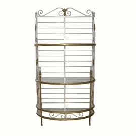 Metal and Glass Etagere: A metal and glass etagere. This tiered shelving unit features a scrolled pediment over a slat back design with demilune glass shelves flanked by scrolled stiles. The unit is finished in a silver tone and brass hue and rests on cap feet.