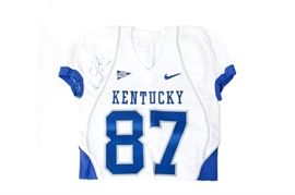 Signed Joker Phillips University of Kentucky Football Jersey: An autographed Joker Phillips University of Kentucky football jersey. This blue and white UK jersey is autographed by Phillips, who coached for the university from 2007-2013, and reads “Joker P, Go Cats!” in blue permanent marker to the upper right sleeve. The jersey is a size L with +4 length and features the number 87.