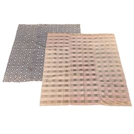 Circa 1890s Handwoven Jacquard Coverlets: A pair of antique coverlets. These circa 1890s jacquard coverlets are handwoven in wool and linen. Each is constructed of three panels in the same pattern, sewn together. One features a latticed pattern of concentric ovals in navy blue over ivory. The other features a checkered pattern of squares and rectangles in pink, black, and white, or pink, blue and white. They are unlabeled.