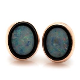 14K Yellow Gold Opal Doublet Earrings: A pair of 14K yellow gold opal doublet earrings. Each earring features a high polish oval body housing a bezel set opal doublet.