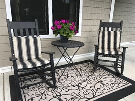 Four black front porch chairs with 2 outdoor rugs
