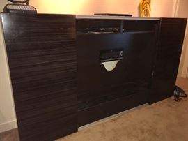 Both right and left side slide toward the center to reveal shelving for clothing or whatever! Center is media center - fits large screen TV and has two shelves for components. Fits tight to the wall - great for small spaces.