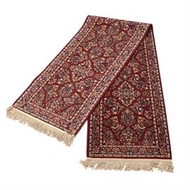 Oriental Hall Runner: An oriental style hall runner rug. It is hand-woven, with floral designs in navy blue, white, orange, and green on a red field. There is fringe to two sides, and the rug is unlabeled. It matches the area rug listed as item 17CIN337-054.