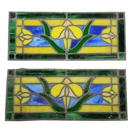 Pair of Antique Stained Glass Panels: A pair of matching hand-crafted custom stained glass panels. The windows have symmetrical tulip decorations across, created with semi-opaque yellow, green, blue, and black glass. The panels were created using lead came, hand-soldered and sealed with the weather-proofing compound. The pieces are not mounted in frames or equipped to hang.