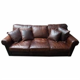 Brown Leather Sleeper Sofa: A sleeper sofa upholstered in brown leather. This sofa has three back cushions, three seat cushions, and rolled arms. The seat cushions can be removed to reveal a pull-out bed. The piece rests upon wooden bun feet and comes with four matching throw pillows.