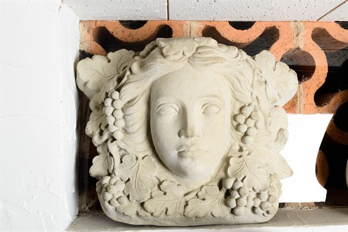 Molded Cement Classical Head Statue: A molded cement head, similar in style to sculpted architectural keystones. The piece depicts a Classical female head with flowing hair, surrounded by grapes and grape leaves. The item is unmarked.