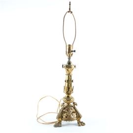 Louis XV Style Brass Table Lamp: A Louis XV style brass table lamp. The lamp features a stem of columnar and globular form decorated with acanthus leaves, floral appliqués and wheat sheafs. It is on a rounded pyramidal base with conforming decoration and three feet decorated with a mythological creature.