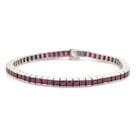 18K White Gold Ruby Tennis Bracelet: An 18K white gold ruby tennis bracelet. This bracelet features half bezel set square faceted rubies set in white gold which closes with a hidden box tab with two figure eight safety clasps.
