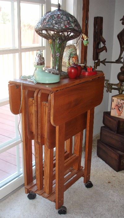 Wood tray tables stored in drop leaf high table on wheels. Tiffany style lamp, blue dial phone