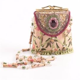 Mary Frances Floral Crossbody Bag: A Mary Frances floral crossbody purse. This handcrafted evening bag features a pink hues floral body with a lattice work of green ribbon embellished with colored rhinestones and crystals. The frame top bag has heavy bead work to top and to one side mimicking a flap with a large multi-faceted black glass bead. A long handle strap of alternating fabric covered beads, colored beads and crystals completes the design. A branded dust cover bag accompanies the the purse.