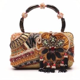 Mary Frances Mixed Trimmings Handbag: A Mary Frances mixed trimmings handbag. The Mary Frances handbag features the handcrafted design including a mixed variety of fabric mediums covered in tassel, soutache, cording and twisted design trimmings. A single arched handle with large tubular wooden and mixed beaded separators completes the design.