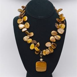 Tiger's Eye Gold Tone Necklace: A tiger’s eye beads and black onyx necklace with a gold tone clasp. This necklace features flat pear-shaped tiger’s eye beads with round black onyx separator beads. It includes a toggle clasp and a square pendant.