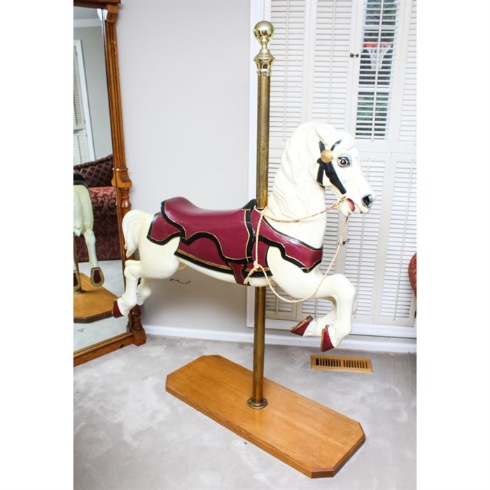 Cast Metal Carousel Horse: A cast metal carousel horse. This cast metal piece features a white painted body with burgundy tack and golden accents. It is attached to a brass pole and rests on an oak base. Base of pole is marked “1/4 Made in U.S.A.”.