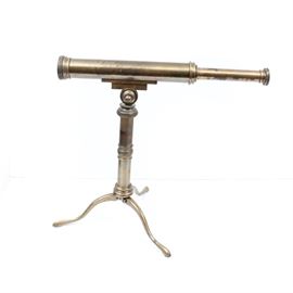 Brass Telescope on Tripod: An antique brass telescope. This piece features brass construction and is mounted on a brass base with folding tripod legs. Piece is unmarked.