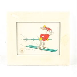 Looney Toons "Snowshoe Bugs" Limited Edition Animation Cel: A Looney Toons “Snowshoe Bugs” limited edition animation cel. This cel, presented in a mat and shrinkwrapped in plastic, features iconic Looney Tunes character Bugs Bunny wearing a red sweater and hat while enjoying some downhill skiing. It has an authentication mark in the lower left from McKimson Productions, Inc. There is a UPC sticker, and “70896 Anim” written on verso.