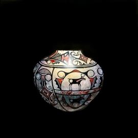 David Herriott Original Oil on Canvas "Zuni Pot Ca. 1890": An original oil painting on canvas titled Zuni Pot Ca. 1890 by Dallas artist David Herriott (1930-2010). Born in Chicago, Herriot attended the University of Illinois, Chicago Art Institute and the American Academy of Art. During the 1950s he served in the U.S. military and eventually settled in Texas where he painted and designed furniture for industrial spaces. The work depicts a late 19th century painted Zuni vessel against a stark black matte gessoed canvas. A single ethereal light source illuminates the top of the pot while the rest of the piece is cast in shadow. Signed to the lower right corner, the work is presented on a gallery wrapped canvas, dated 6-1-88 and signed to its verso. The piece is wired to its back for hanging.