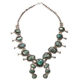 Signed J.W. Squash Blossom Necklace: A signed J.W. squash blossom necklace. The necklace features a length of approximately 27.00", ten green turquoise stones to the neck piece with blossoms and seven green turquoise to its center. The piece is stamped J.W. to its verso and is finished with a hook and eye closure. Unstamped, the silver tested as 91.65% pure when evaluated. Total approximate weight, inclusive of all materials, is 8.580 ozt.