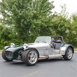 1969 Birkin Lotus 7 Roadster: A 1969 Lotus 7 replica kit car by Birkin; VIN is K1NU1AB1120 and odometer reads 2,293 miles. This model S3 American kit car is body style 2D. Vehicle has a 4-cylinder modified Ford Z Tech 1600 engine, DOHC, dual K&N carburetors, and timing belt motor. There is a five-speed manual transmission with hydraulic clutch and master cylinder for front and rear brakes. Windshield wipers, washer fluid pump, heater, and spare tire have been added. Vehicle features two black vinyl upholstered seats, a removable steering wheel, 16" alloy wheels, exposed exhaust system to driver’s side, rag top, racing green fiberglass fenders, and black powder coated steel roll bar. Behind the seats is a black canvas tonneau cover over the rear storage compartment. Caterham Cars, a British manufacturer of specialist lightweight sports cars, bought mold rights for this body and frame from Lotus in 1965.