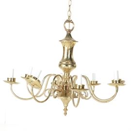 Brass Tone Chandelier: A brass tone chandelier. The colonial style chandelier features an urn style column with eight arms holding white candle look fixtures.