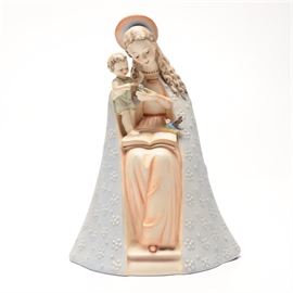Goebel Hummel Flower Madonna and Child Figure: A Hummel Flower Madonna and Child figure. This piece depicts the Virgin Mary, wearing a peach dress, blue shroud, and halo, sitting with an open book in her lap and the child Jesus in her arms. She is holding a flower in one hand which the child is reaching for while a bird perches in her lap.