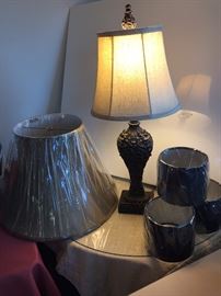 Carved wooden lamp on top of a 30" round skirted table (fabric and glass). Multiple unused shades.