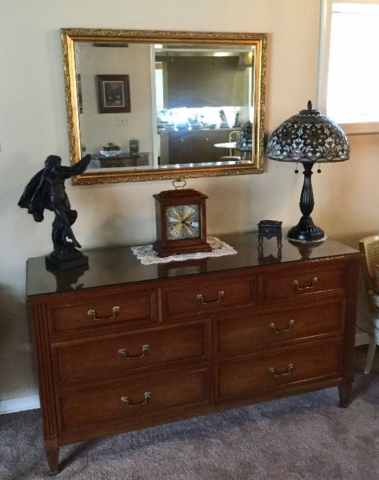 Beautiful Kindle dresser used as a buffet, has a glass top. Sculpture and Tiffany style lamp showcased under a wonderful gilt mirror