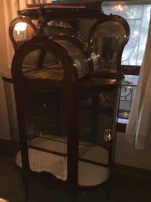 Antique Curved beveled glass Curio Cabinet in Excellent condition.  This one is a truly beautiful piece with unique details carved in a rich mahogany. 