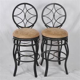 Pair of Metal Swivel Bar Chairs: A pair of contemporary bar chairs. These chairs have metal frames with a black finish and tan upholstered cushions.