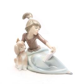 Lladró "A Lesson Shared" Figurine #5475: A Lladró figurine titled A Lesson Shared, #5475. The figurine depicts a girl reclining with a school book. Her dog sits next to her with his head cocked, appearing to help with her lessons. The piece was originally sculpted by Juan Huerta in 1988 and retired in 1992. The piece is signed “M. Lladro” to the underside and dated “5/16/88”.
