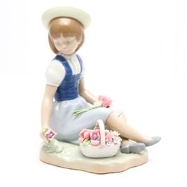 Lladró Figurine "With Wild Flowers" #1287: A Lladró figurine titled With Wild Flowers, #1287. The piece depicts a young girl sitting on the grass with her legs crossed, she is gazing to the side. She holds a pink flower in one hand, and a flower on her lap. Her basket is filled with pink flowers. The piece was sculpted by Francisco Catala and issued in 1974; retired in 1998.