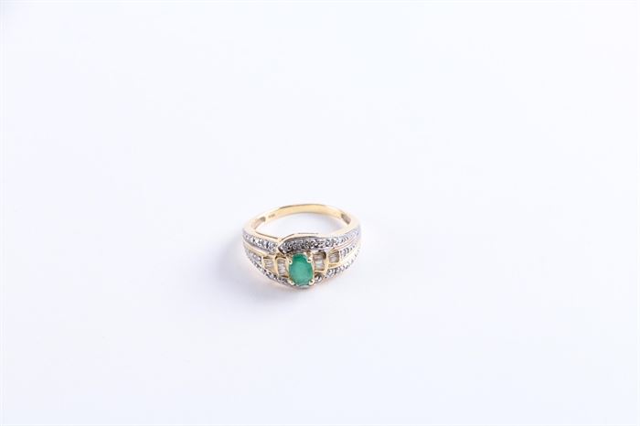 14K Yellow Gold Emerald and Diamond Ring: A 14K gold emerald and diamond cocktail ring. This ring features an emerald center stone flanked by ten baguette diamonds surrounded by embossed silver tone trim.