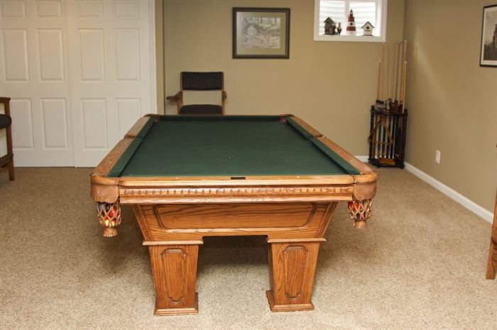 Kasson Oak Billiards Table and Ping Pong Table Top: An exquisite Kasson oak billiards table. This Tudor model table features solid oak construction, a slate top with green felt, mother of pearl inlays, hand-crafted leather pockets, notched wood trim with raised panel styling throughout and tapered body and legs. Also included with the table are a protective covering, a set of billiard balls, racks, cue sticks with storage case, chalks, cleaning brushes and supplies and a wooden ping pong game table cover, net, paddles and balls.