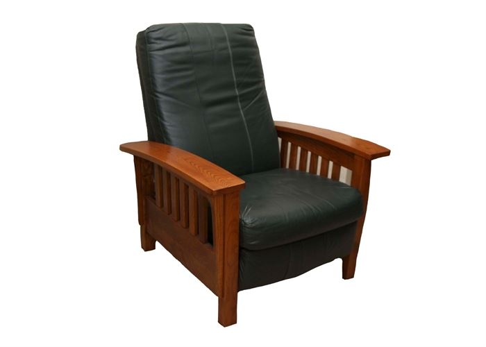 Mission Style Reclining Armchair: A Mission style reclining armchair. This chair has an oak wood frame finished in a warm brown stain. It features slightly curved arm rests over rails and straight legs. Upholstered in dark green leather, the chair reclines for comfort.