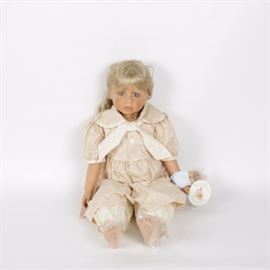 Limited edition "Amber" Masterpiece Gallery Doll: A limited edition Amber doll from Masterpiece Gallery. This porcelain doll is number 071 out of a release of 750 and was designed by artist Pamela Erff. It features a blonde doll with a side braid adorned in a beige floral print jumper with a large bow collar, a Peter Rabbit plush toy around her wrist, and plastic wrapped feet. The doll finishes with beautifully detailed facial features and lashes to the rich blue eyes. The original box and Certificate of Authenticity are included.