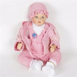 Limited Edition "Theresa" Masterpiece Gallery Doll: A limited edition Theresa doll from Masterpiece Gallery. This porcelain doll is number 119 out of a release of 600 and was designed by German artist Monika Levenig. It presents in a plaid pink jumper, jacket, and bonnet with a butterfly brooch and bright blue eyes accented by lush lashes. The original box and Certificate of Authenticity are included.