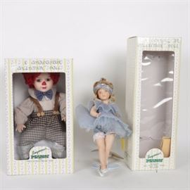 Two Seymour Mann Porcelain Dolls: A pair of porcelain dolls by Seymour Mann. Includes Little Pavlova, the first in the Tiny Tots series. The doll presents with blonde hair, wearing a pleated periwinkle tutu with silver threaded trim and slippers. Presents in an original box with paperwork and a Certificate of Authenticity, number 3027726. Also included is a boy clown doll with red hair and nose, wearing plaid pants with suspenders and a blue and white checkered bow tie. Presents in original box.