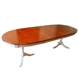 Oval Dining Table with Cherry Top and Painted Base: A large oval dining table with a cherry veneer wood top and a white distress painted base. Two leaves are included. The base sits on two turned pedestals, each with three splayed feet.
