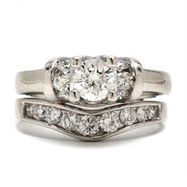 14K White Gold 1.42 CTW Diamond Bridal Ring Set: A 14K white gold bridal ring set including an engagement ring with a center diamond along with channel-set accent diamonds set to all three sides. The soldered wedding band has a row of diamonds with a slightly curved center. The total diamond carat weight between the set is 1.42 ctw.