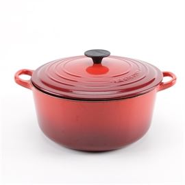 Cerise Le Creuset Lidded Pot: A lidded pot from Le Creuset in the cerise color. This pot has fixed handles, and a relatively flat lid with a black knob, marked “Le Creuset”. The interior is light tan, and the underside is stamped “Le Creuset 26 France”.