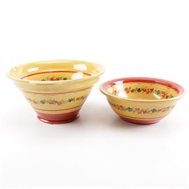 Terre è Provence Mixing Bowls: A pair of Terre è Provence mixing bowls. This pair of ceramic mixing bowls are presented in yellow and red and include floral detailing on both their exterior and interior. The bowls include one which is tapered with two protruding handles at its top and a smaller bowl with a lipped edge. The bowls are marked “Terre è Provence Made in France” to their underside.