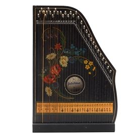 Jubeltone Children's Zither 303: A_ Jubeltone Children’s Zither 303_. This German made stringed instrument has a black frame embellished with a colorful floral motif. The box it comes in is marked “Made in Germany” and includes instructions, and ten pieces of sheet music, that are written in English and German. Printed to the inside is “Jubeltone Konzert Salon Harfe Qualifatsmarke”. Marked to the back is “Made in Western Germany”.